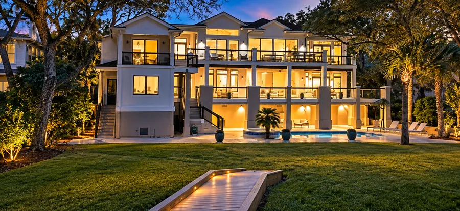 Estate at twilight from the lawn, lit walkway leading to the pool